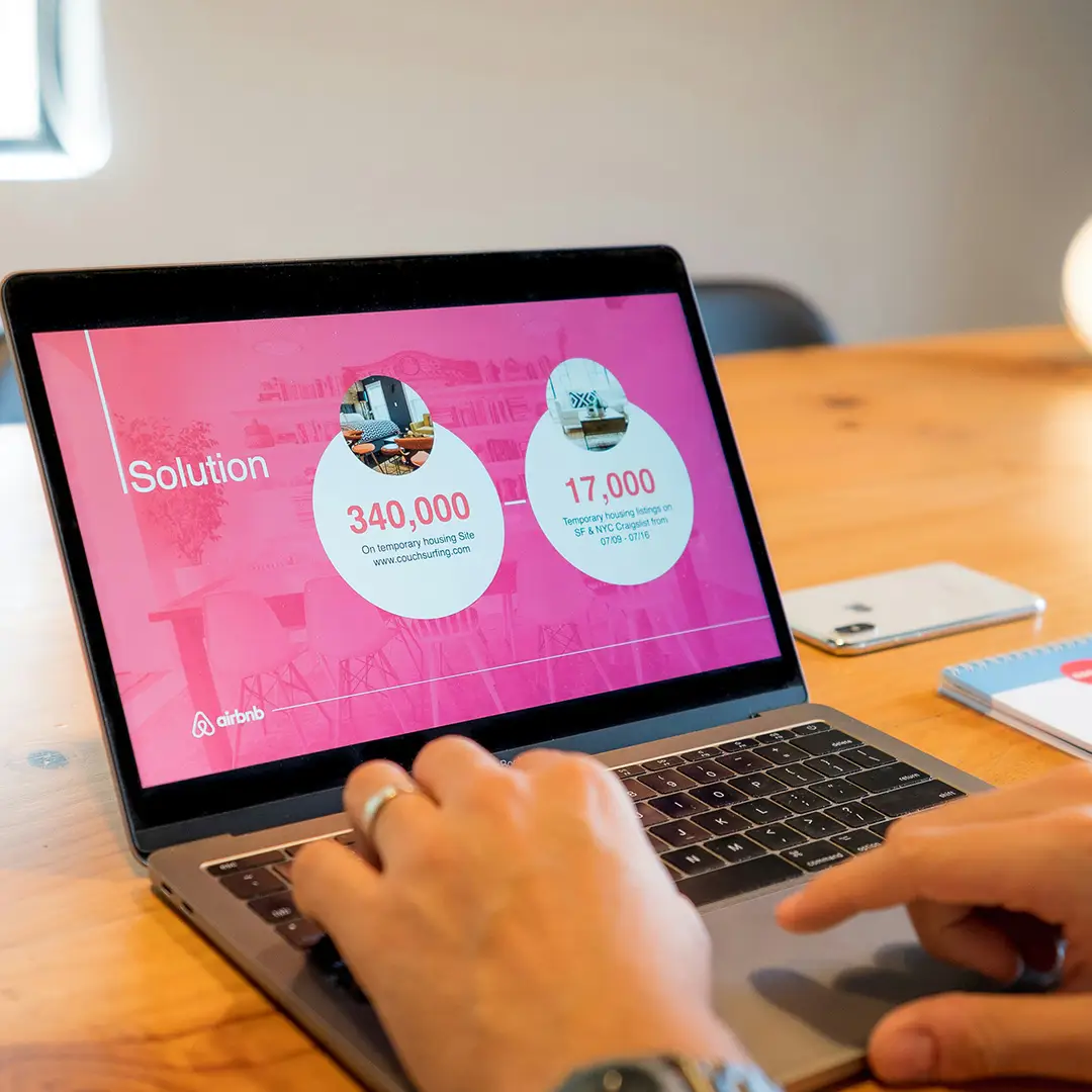 Person working on a laptop showing a presentation slide deck, representing the process of shaping content, data and visual storytelling into a clear presentation.