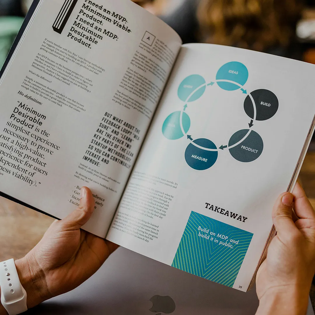 Reader viewing an editorial report spread featuring a circular product-development process diagram.