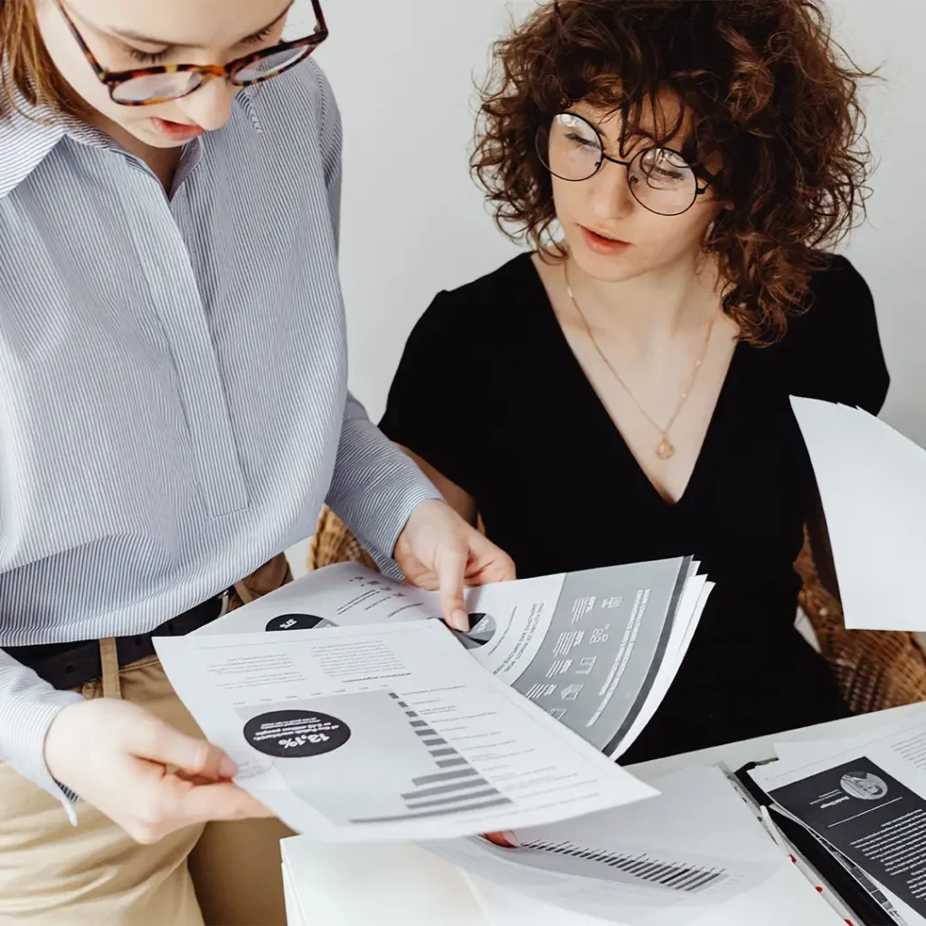 Two colleagues reviewing printed reports and data visualisations together.