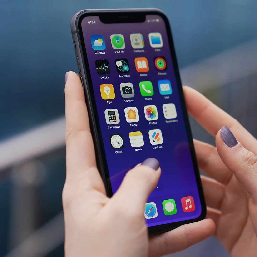 Person using a smartphone with app icons displayed on the screen.